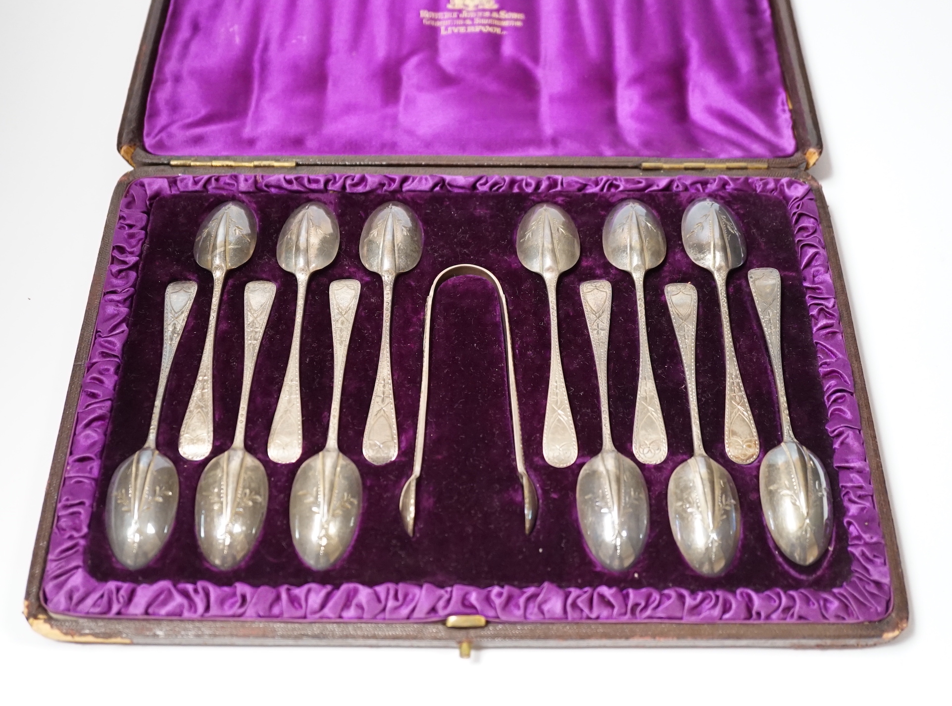 A cased set of twelve Victorian engraved silver rat tail pattern teaspoons with sugar tongs, George Adams, London, 1882.
